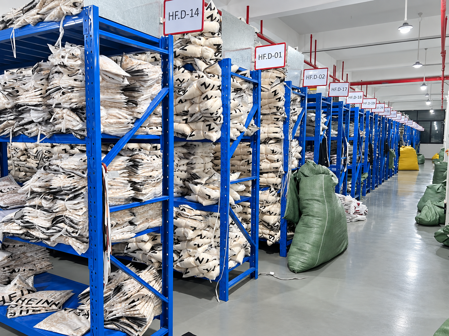 Organized garment storage racks and a clear aisle inside the HUAJUN warehouse