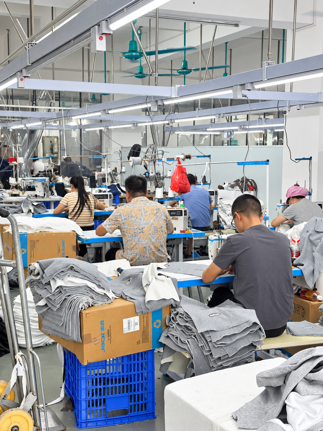 Rows of sewing stations and industrial sewing machines inside the HUAJUN workshop